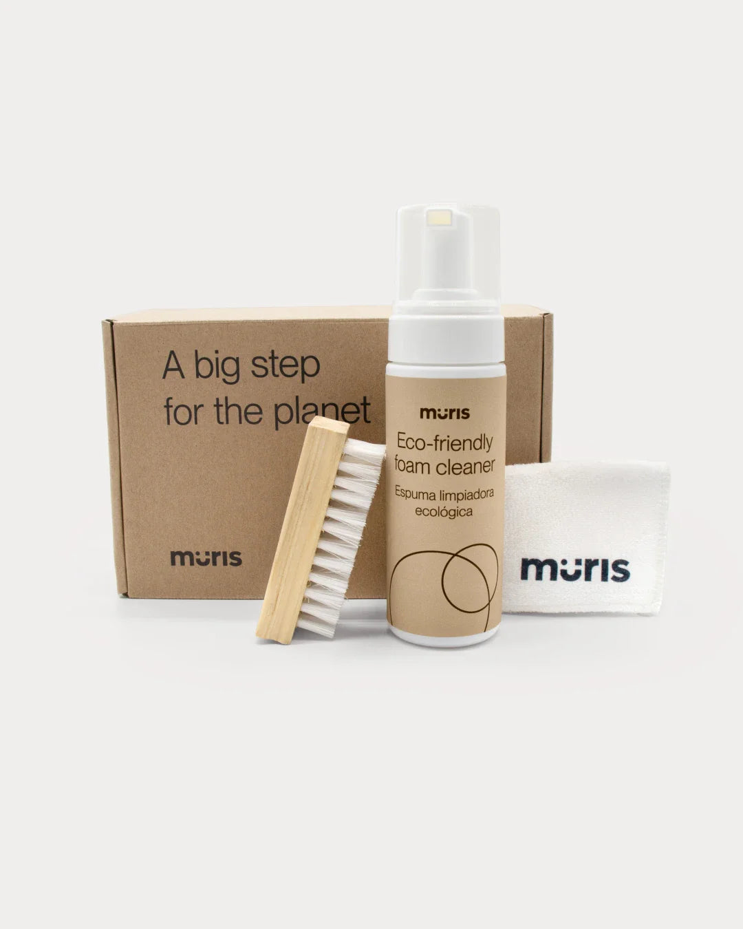 Kit de limpeza ecológico Muris com espuma, escova de madeira e pano de algodão orgânico, sobre uma caixa de cartão.