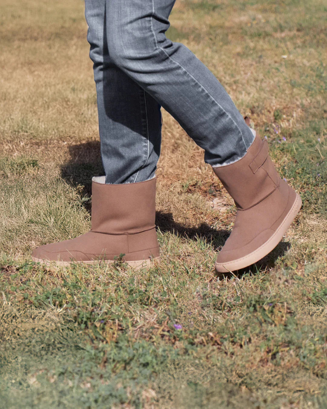 Pessoa a caminhar com as botas Muris Barefoot Siberia Adulto, destacando a sola flexível e o design minimalista. Calçado barefoot quente e respirável.

