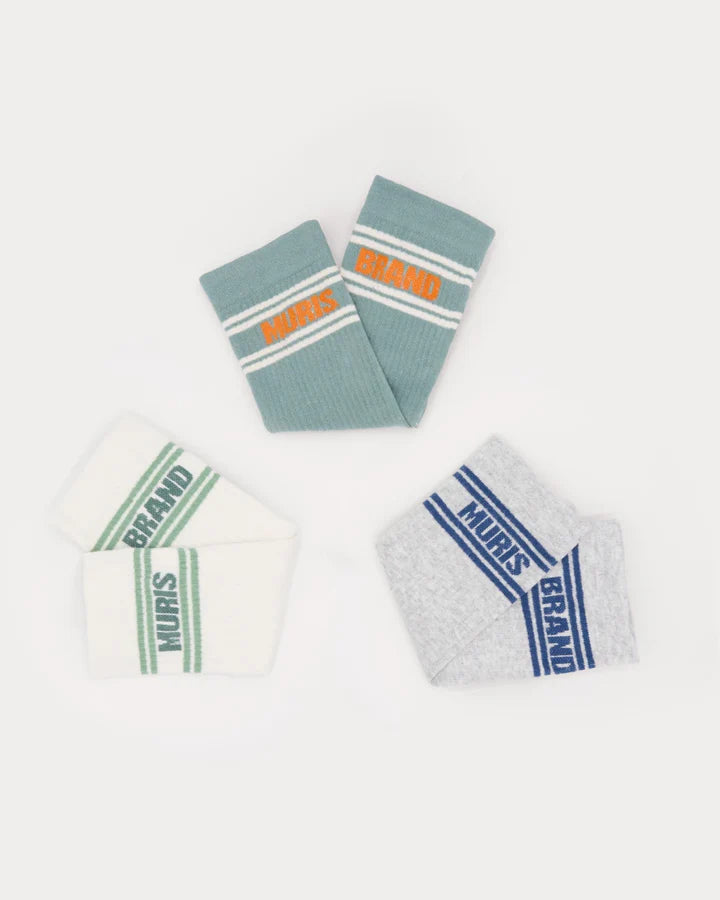 Três pares de meias Muris Respeitadoras Homem dobradas, em tons de azul-esverdeado, branco e cinzento, com riscas e o logótipo "MURIS" em cores contrastantes.