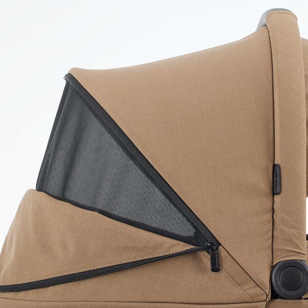 Detalhe da capota do carrinho Mutsy Flow cor castanha, mostrando a zona de ventilação em rede preta, fechada com fecho éclair.