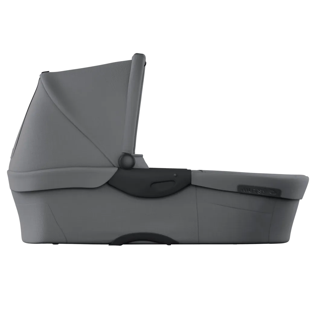 Alcofa Mutsy Evo cinzento claro, vista lateral, com capota ajustável e pega de transporte escura.