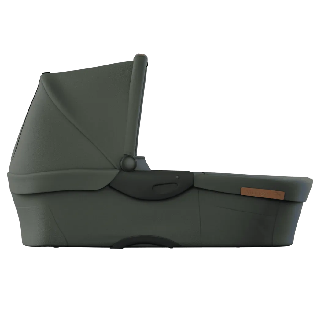 Alcofa Mutsy Evo em cor verde-acinzentada escura, vista de perfil, com capota ajustável e pega de transporte escura.