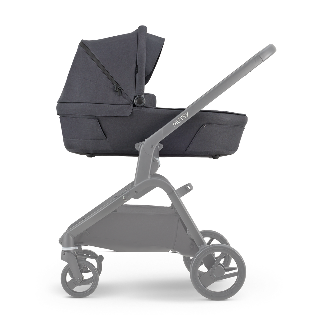 Alcofa Mutsy Flow em cor escura (North Black) montada no chassis cinzento, vista lateral, destacando o design moderno.