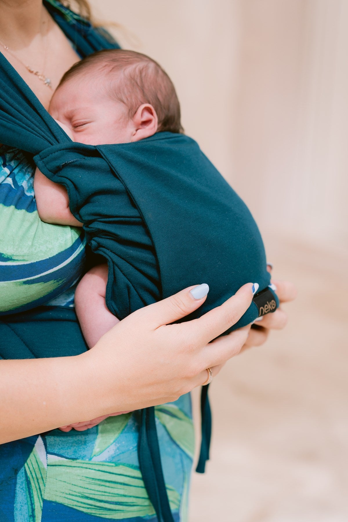 Close-up de bebé recém-nascido a dormir na mochila de babywearing Neko Tiny cor teal, mostrando o tecido macio e a etiqueta Neko.