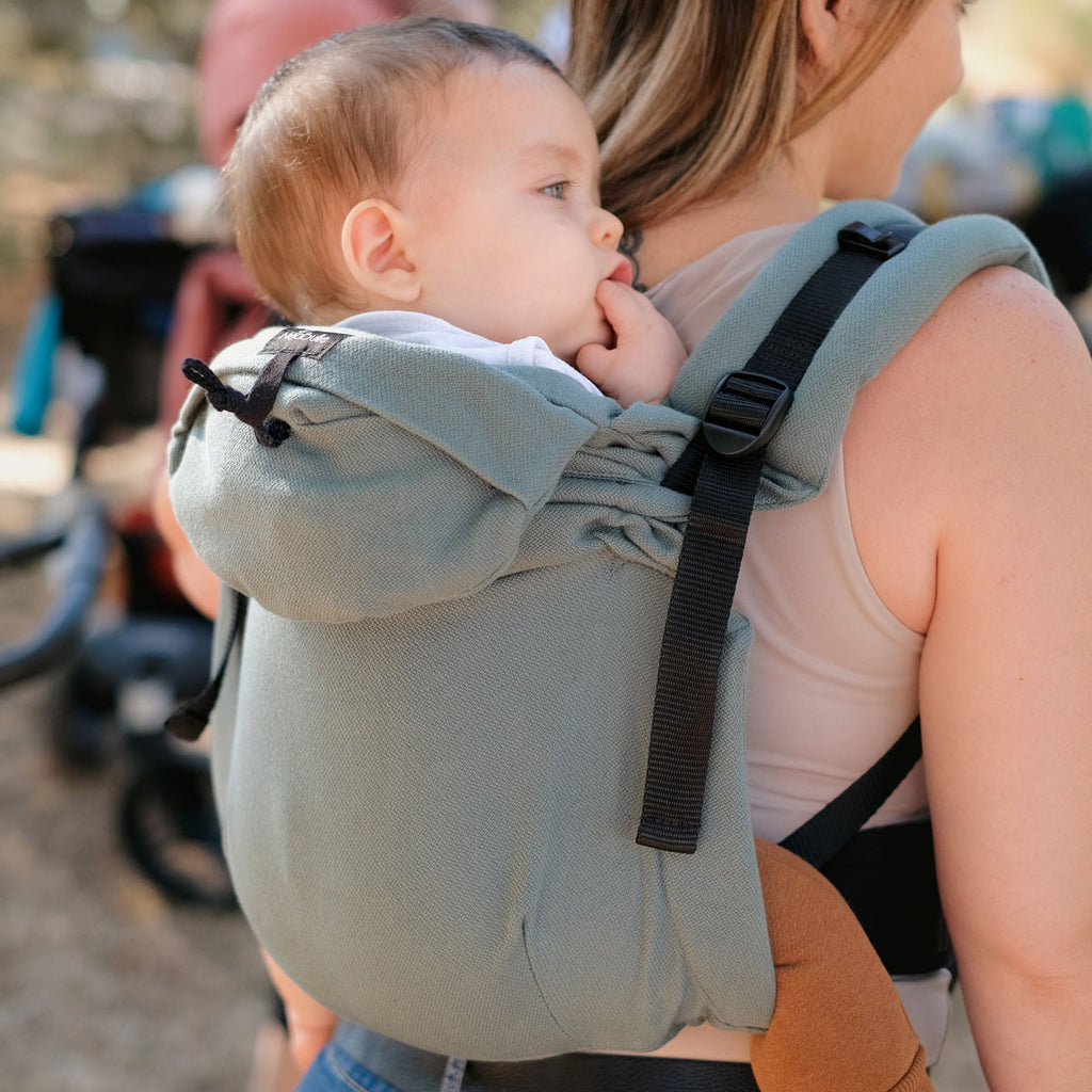 Mãe e bebé a passear ao ar livre com a mochila ajustável, destacando o conforto e o ajuste seguro.