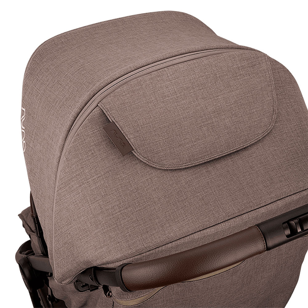 Detalhe da capota extensível do carrinho Nuna TRVL LX, em tecido castanho, com fecho para expansão e aba de ventilação.