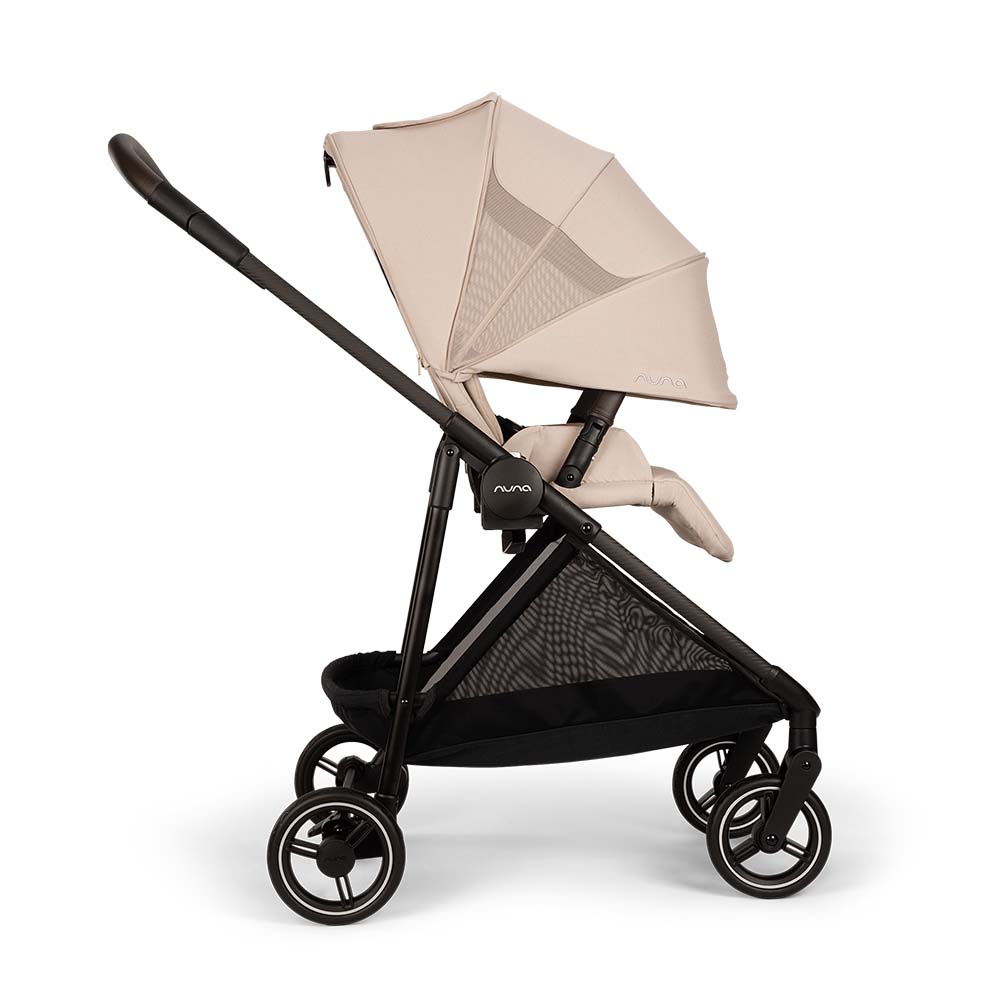 Carrinho de passeio Nuna IXXA NEXT bege com estrutura preta, assento reclinado e capota aberta, visto de lado.