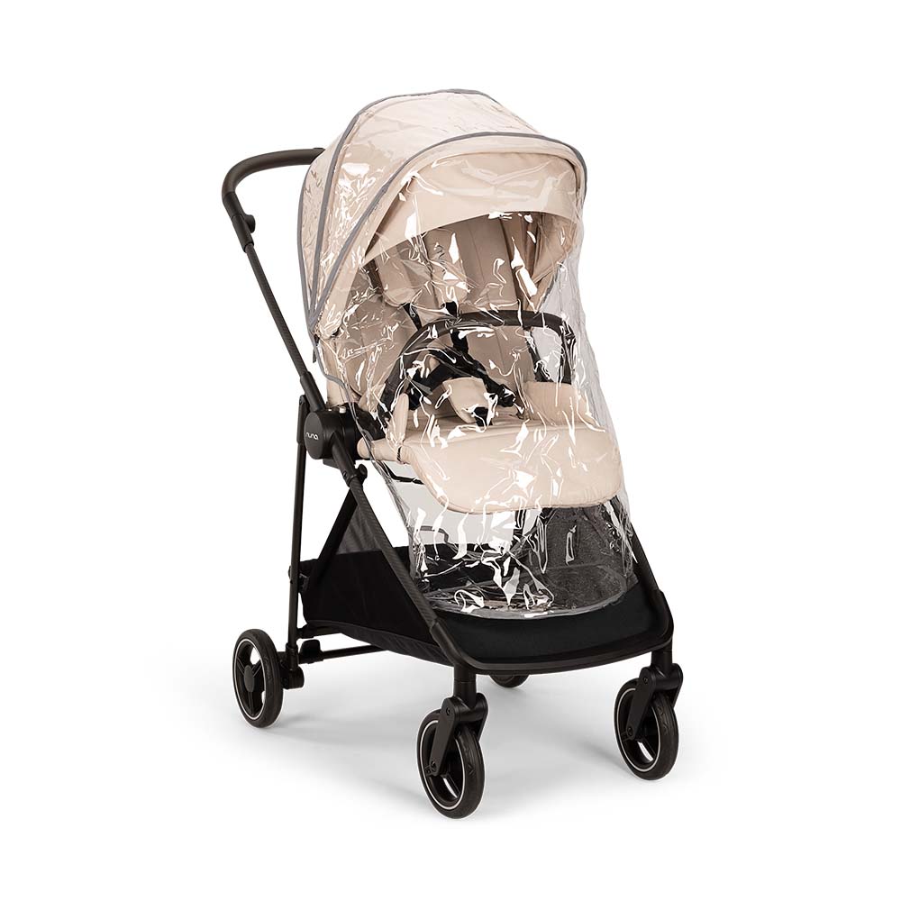 Carrinho Nuna IXXA NEXT bege protegido com capa de chuva transparente, pronto para uso em tempo húmido.