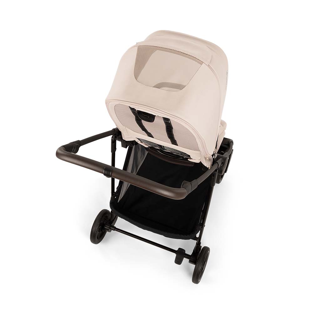 Perspetiva superior do carrinho Nuna IXXA NEXT bege, destacando a pega ajustável em pele sintética e o cesto de arrumação.