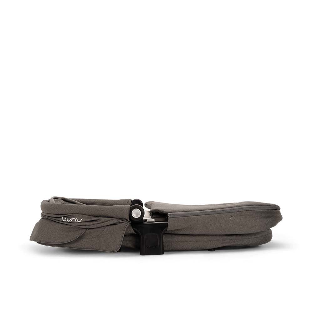 Alcofa Nuna SWIV dobrada e compacta, vista lateralmente, demonstrando a facilidade de arrumação.