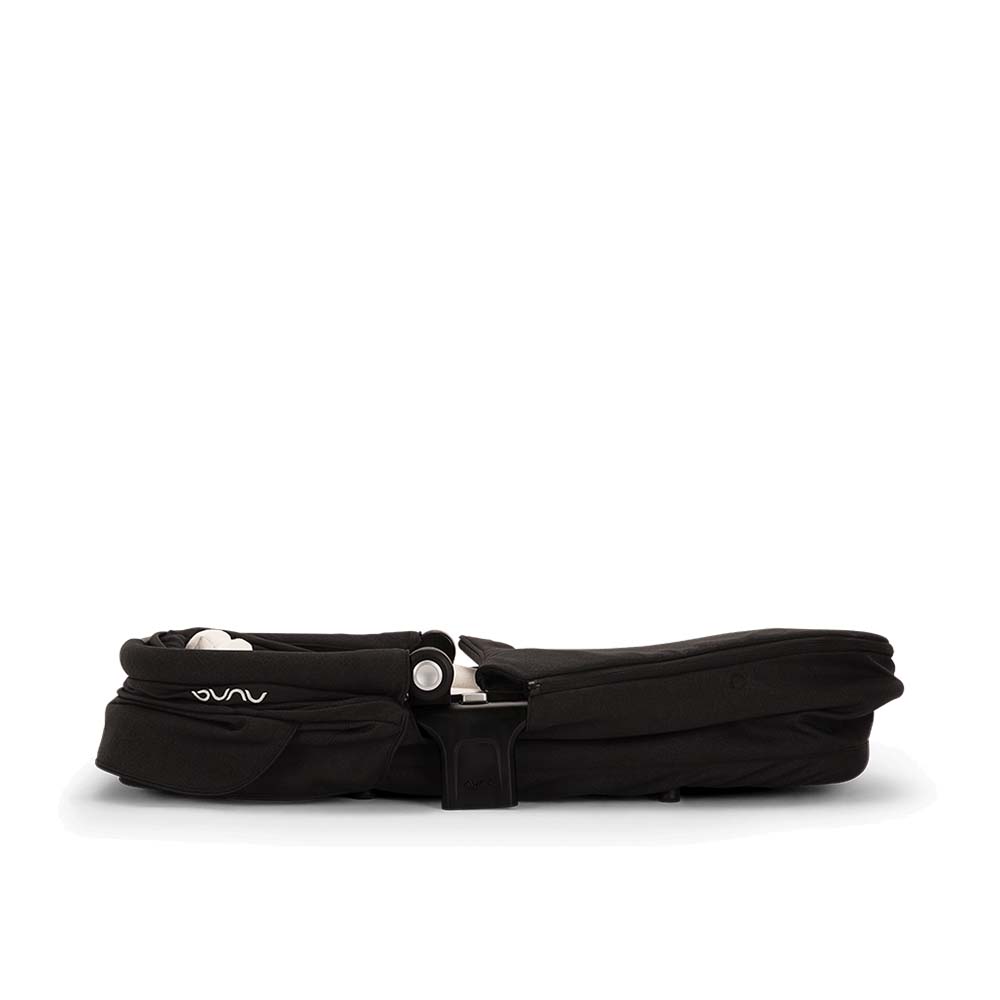 Alcofa Nuna dobrada e compacta, vista de lado, ilustrando a facilidade de arrumação do acessório.