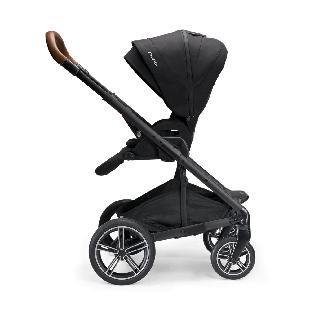 Carrinho de passeio Nuna MIXX NEXT preto, visto de lado, com assento reclinado e pega em pele castanha.