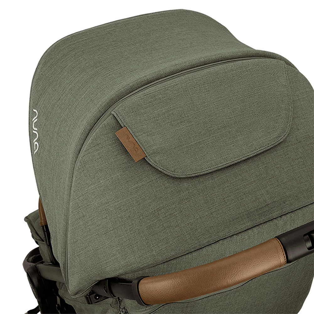 Detalhe da capota extensível verde azeitona do carrinho Nuna TRVL LX com fecho magnético e guiador em pele castanha.