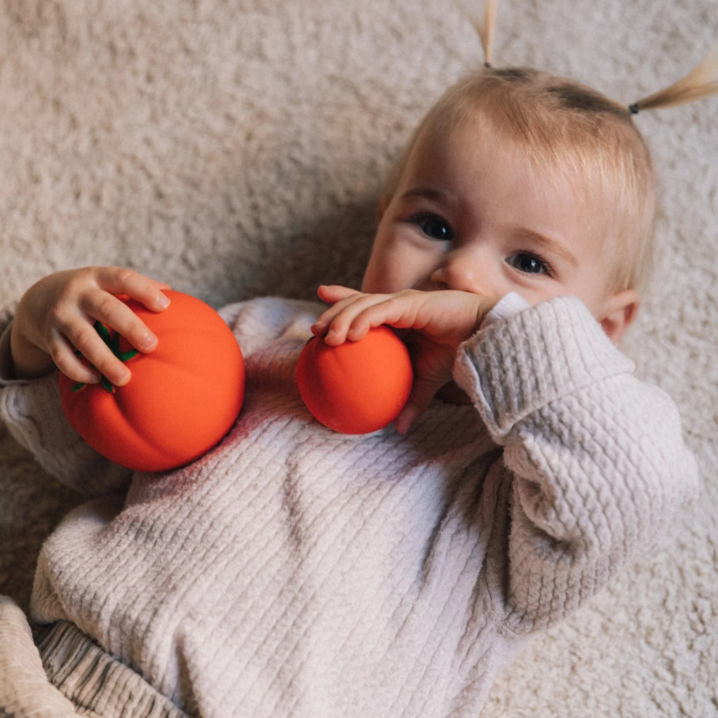 Bebé brincando com as bolas sensoriais de tomate Oli & Carol. Mordedor seguro e ecológico para bebés a partir dos 7 meses.