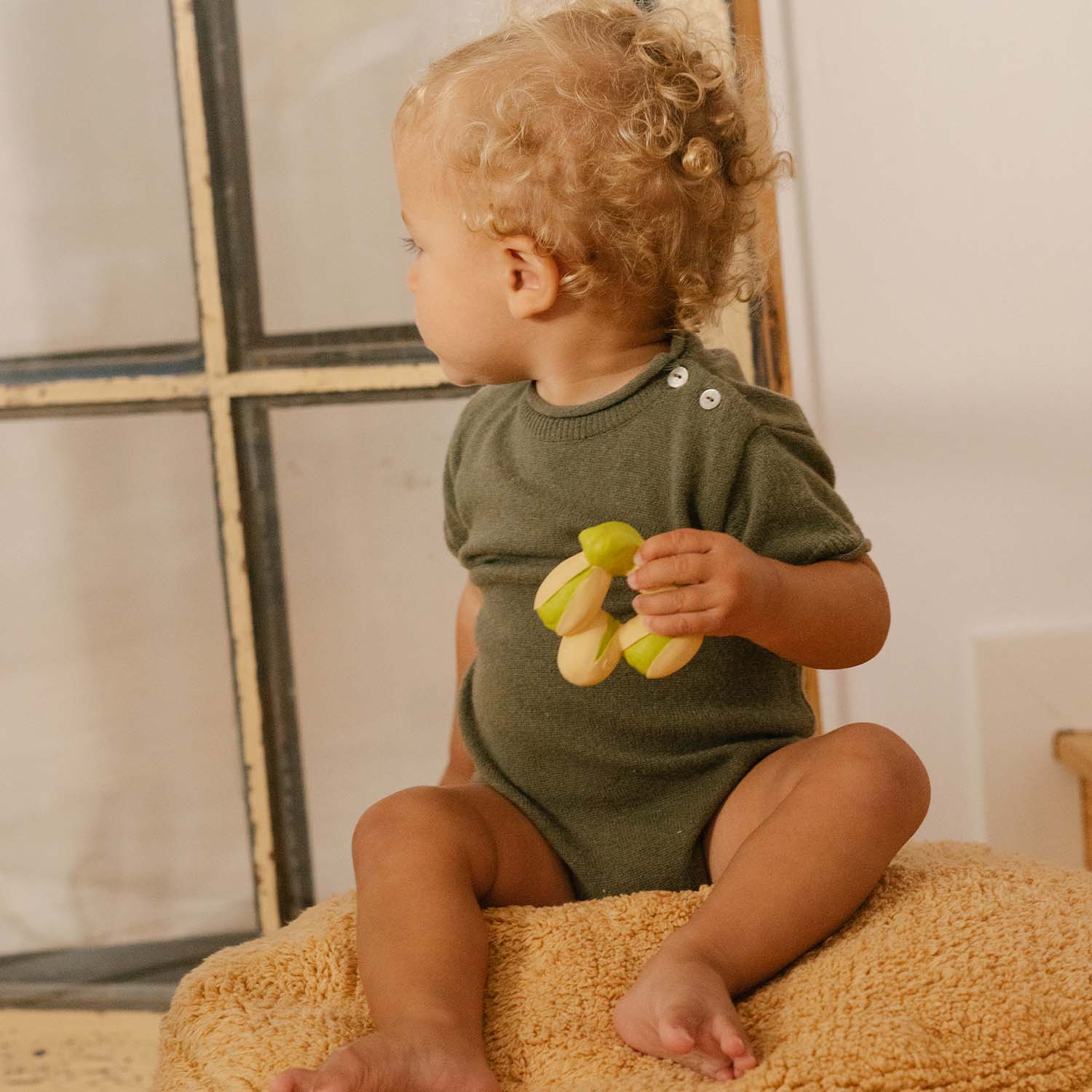 Bebê brincando com o mordedor Patrício o Pistachio da Oli & Carol. Brinquedo de borracha natural para dentição e banho.