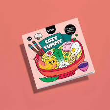 Capa do caderno de colorir OMY "Cozy Yummy" com ilustração de um prato de ramen colorido, sobre fundo rosa.