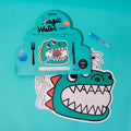 Embalagem do conjunto OMY Magic Water Dinos, mostrando dois individuais reutilizáveis e a caneta mágica, sobre fundo azul-turquesa.