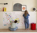 Duas meninas sentadas no chão a colorir um poster gigante da OMY com desenhos de todo o mundo.