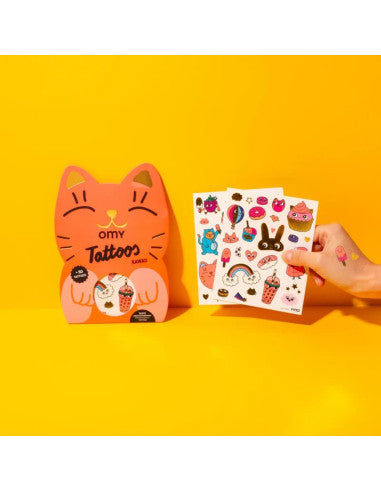 Embalagem OMY Tatuagens Kawai em forma de gato laranja, com folhas de tatuagens temporárias coloridas (comida, arco-íris) a serem mostradas ao lado.