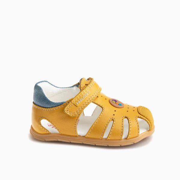 Sandália infantil Pablosky Barefoot Savana Tuorlo em pele amarela, vista lateral, com fecho de velcro e detalhe azul no calcanhar.