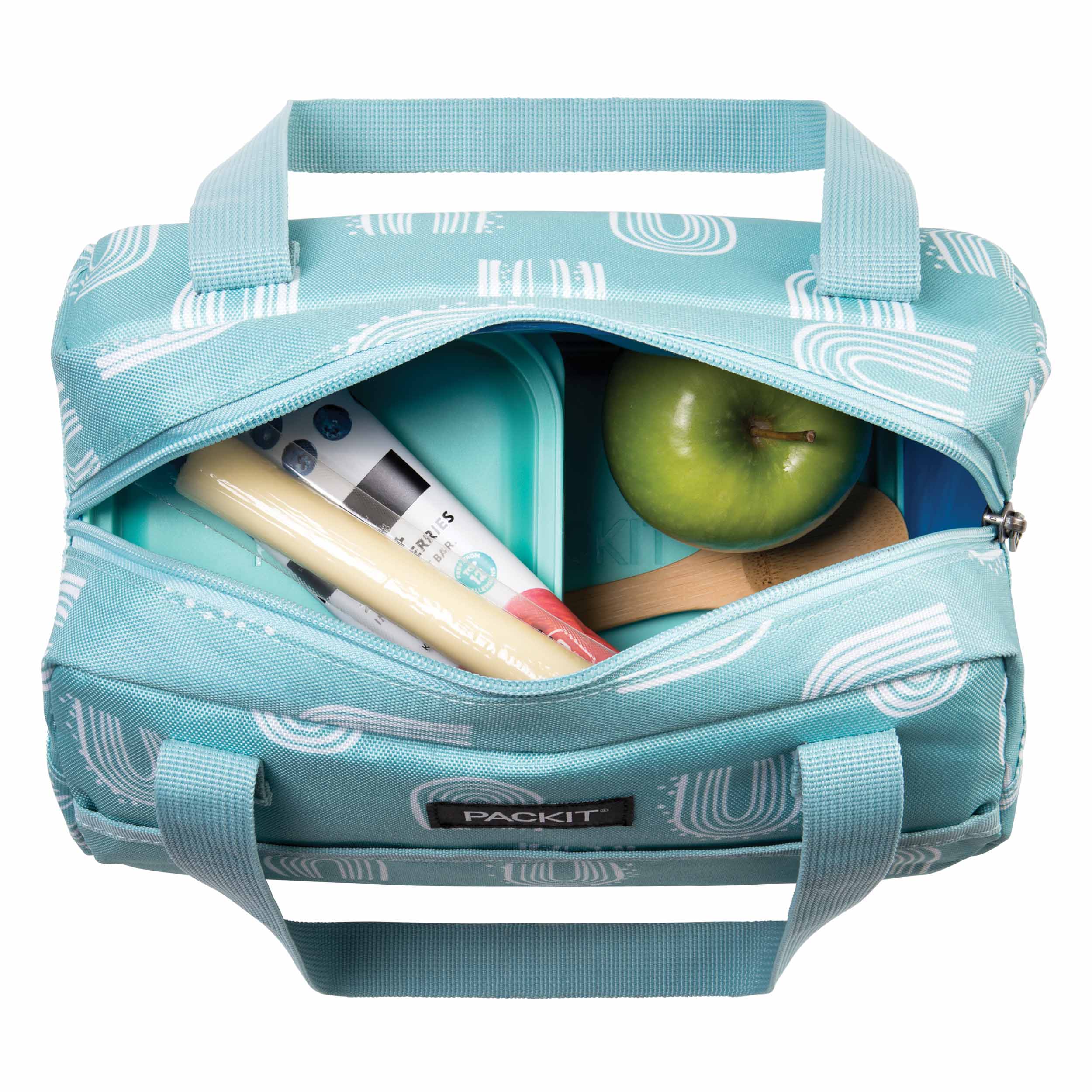 Vista superior da bolsa lancheira Packit aberta, mostrando o interior com um recipiente azul, uma maçã verde e um snack embalado, mantidos frescos.