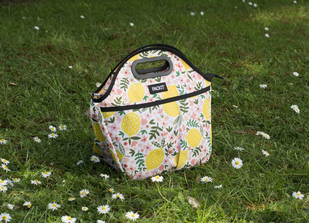 Bolsa lancheira Packit com fecho de correr, destacando a asa de transporte e o design compacto com padrão limões.