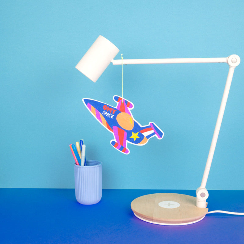 Decoração de foguetão OMY Cosmos suspensa numa secretária com candeeiro, mostrando o resultado final colorido.