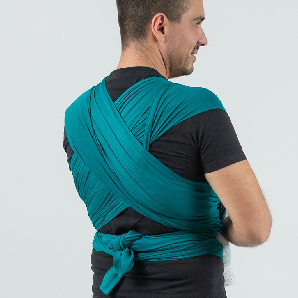 Vista traseira de um homem a usar o pano elástico Isara TANBOOCEL BAMBOO Teal Green, mostrando o nó seguro e o suporte cruzado nas costas.