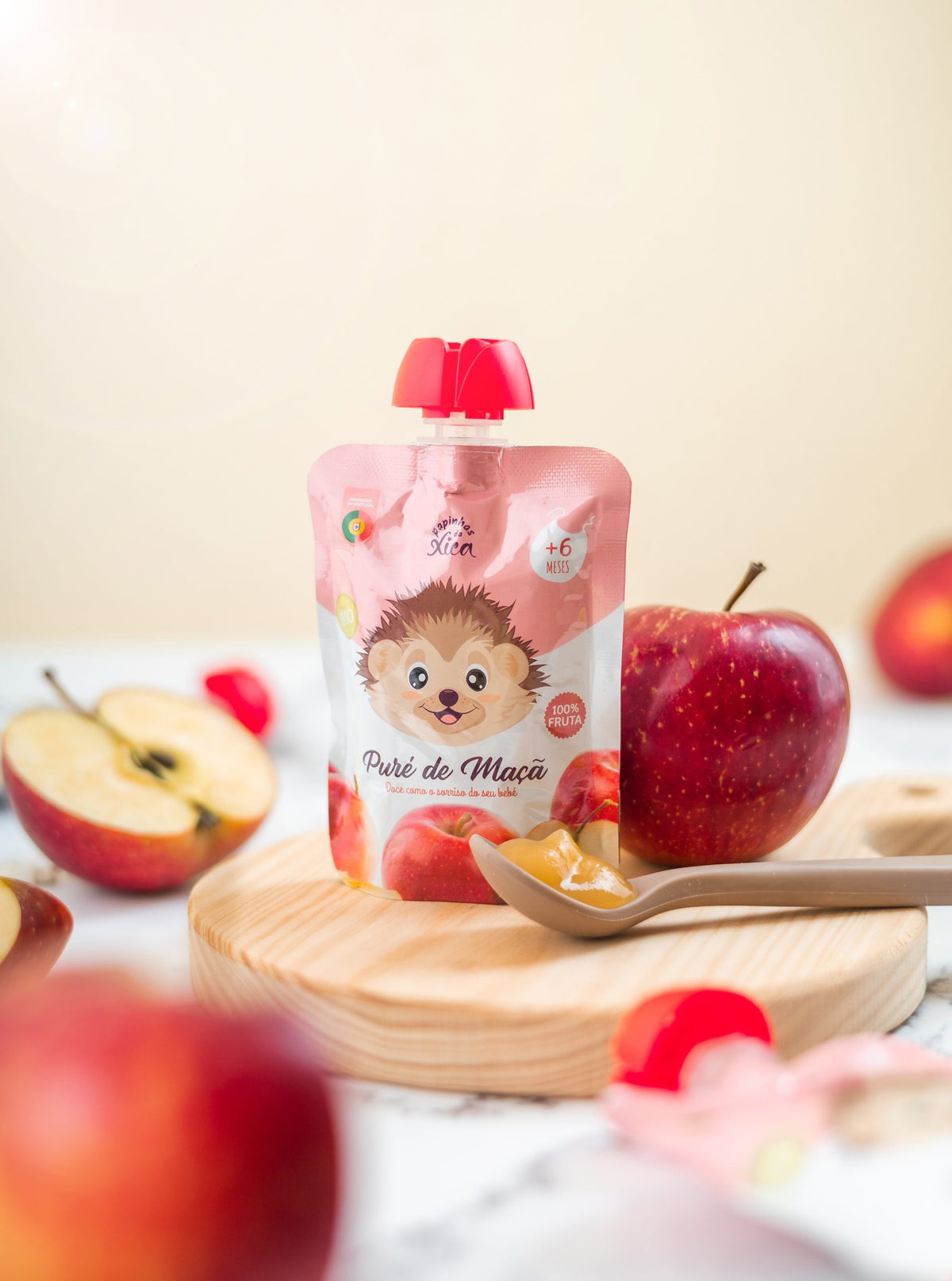 Puré de Maçã Biológico Papinhas da Xica em saqueta, com maçãs frescas e puré numa colher, ideal para bebés.