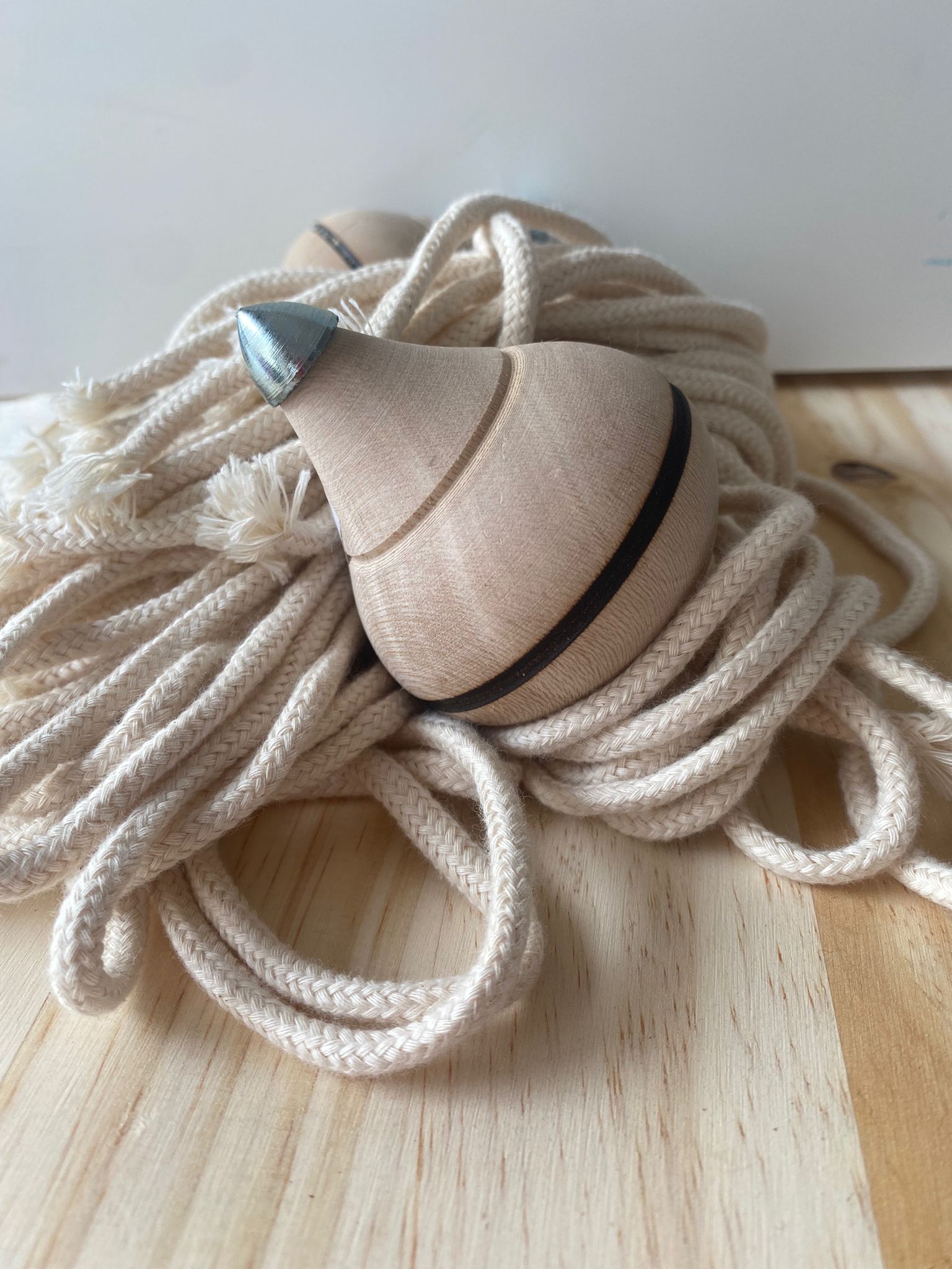 Detalhe da ponta metálica de um pião tradicional de madeira, assente sobre o baraço (cordão) branco.