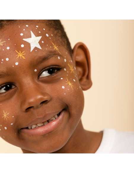 Detalhe do rosto de um menino com pinturas faciais de estrelas brancas e douradas feitas com marcadores Nailmatic.