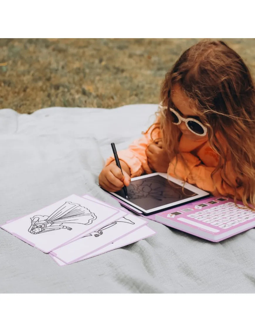 Menina a usar o tablet de desenho KidyWolf Princesas ao ar livre, a decalcar uma ilustração numa manta de piquenique.