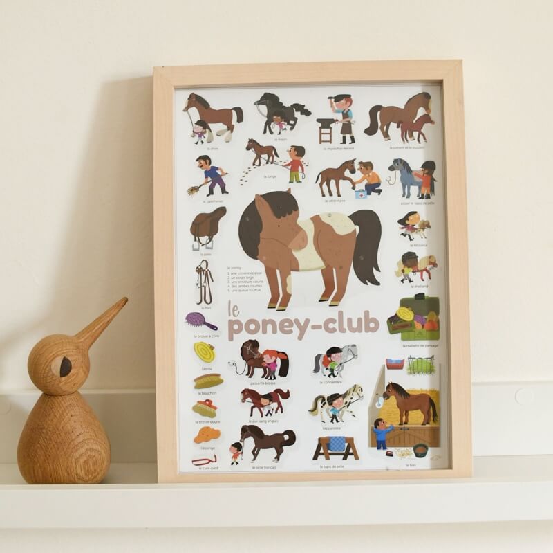 Poster educativo "Le Poney-Club" da Poppik, emoldurado, com autocolantes de cavalos, crianças e acessórios, decorando uma prateleira com um objeto de madeira.