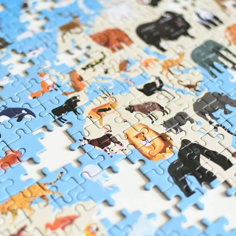 Detalhe em close-up de peças parcialmente montadas do puzzle Poppik Animals, mostrando a qualidade da impressão e a ilustração de vários animais africanos no mapa.