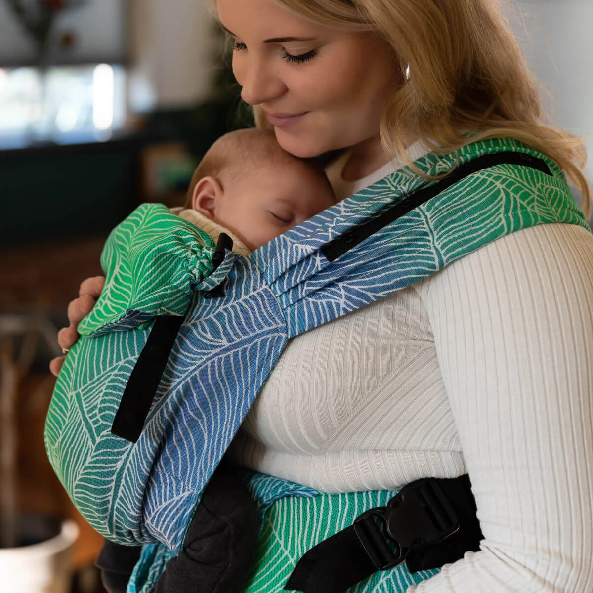 Mãe com bebé na mochila Primeo, destacando a posição ergonómica do bebé.