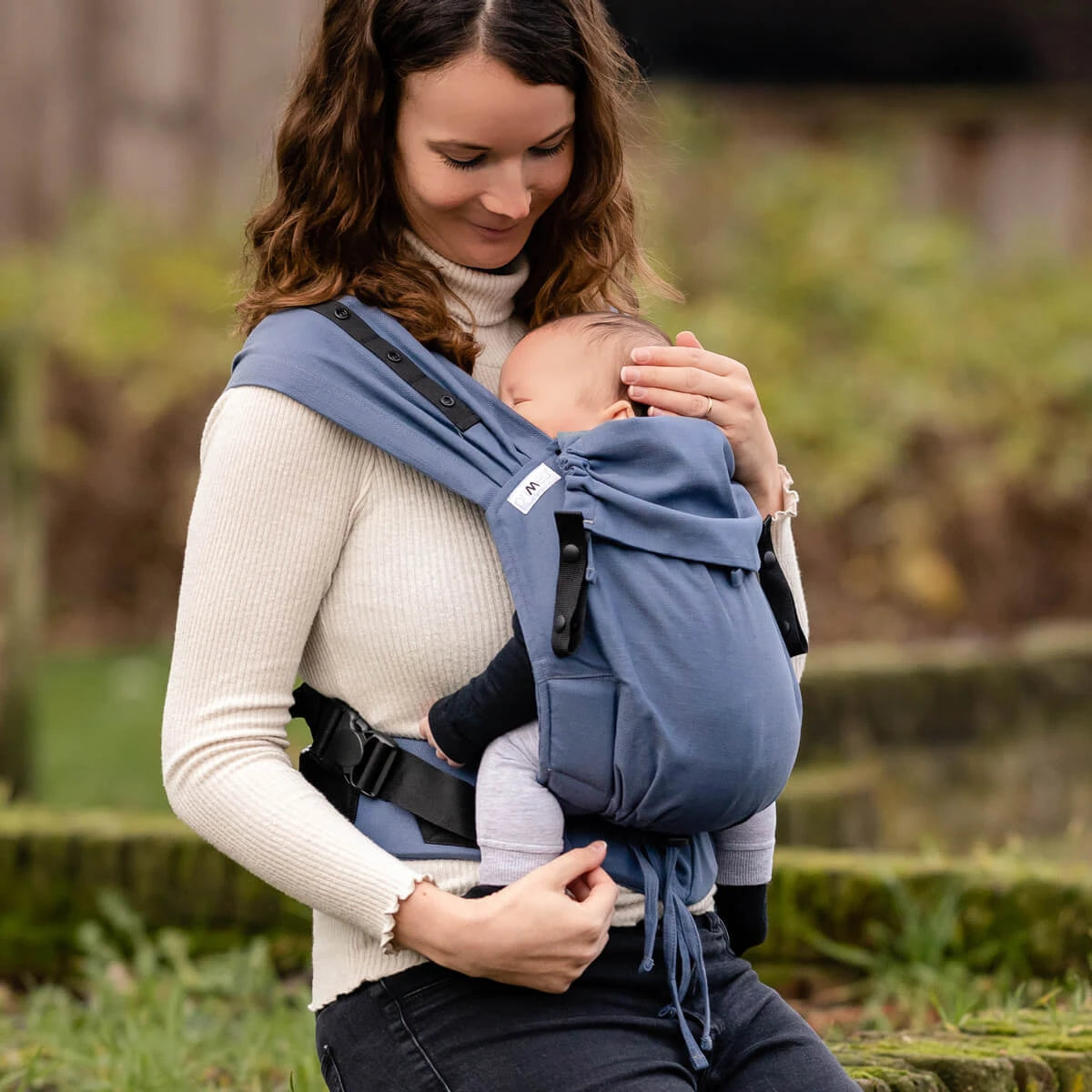 Mulher a usar a mochila Hoppediz Primeo Crete com bebé à frente.