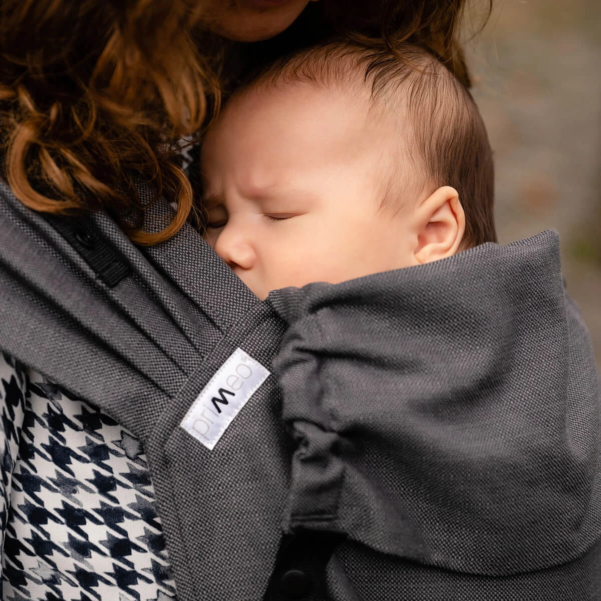 Bebé a dormir confortavelmente na mochila Hoppediz Primeo, próximo ao peito da mãe.