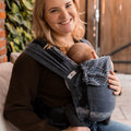 Mãe sorridente a usar a mochila Hoppediz Primeo Sapporo com o bebé.