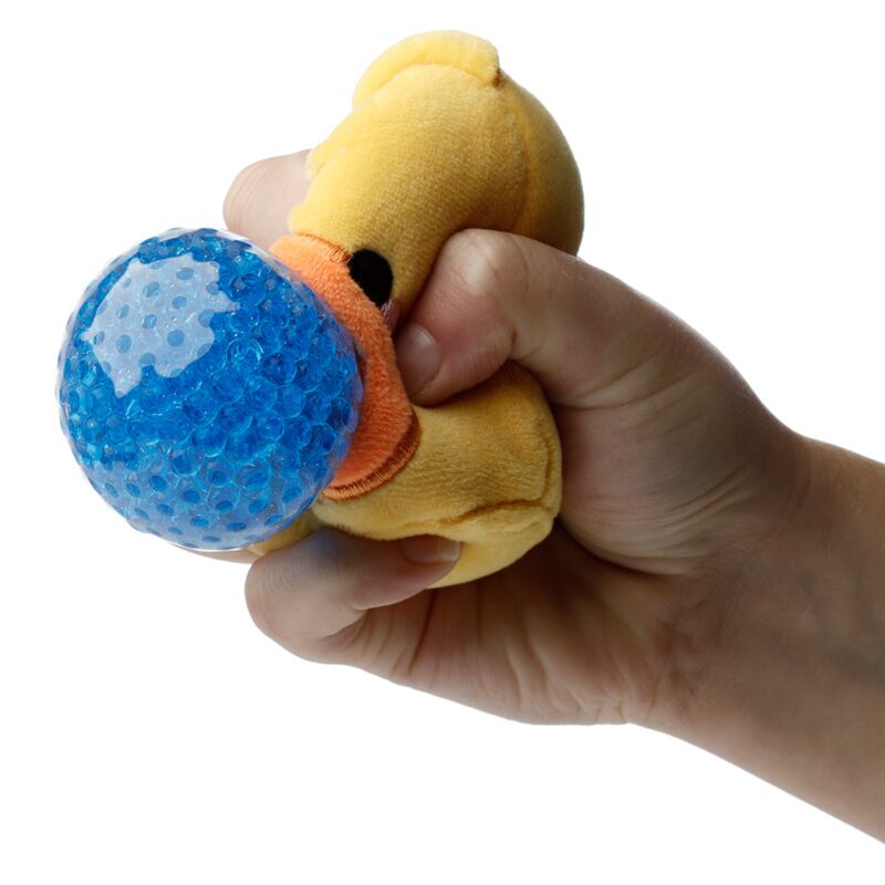 Uma mão a apertar um brinquedo Queasy Squeezies Adoramals em forma de pintinho, mostrando a bola espremível azul no interior.