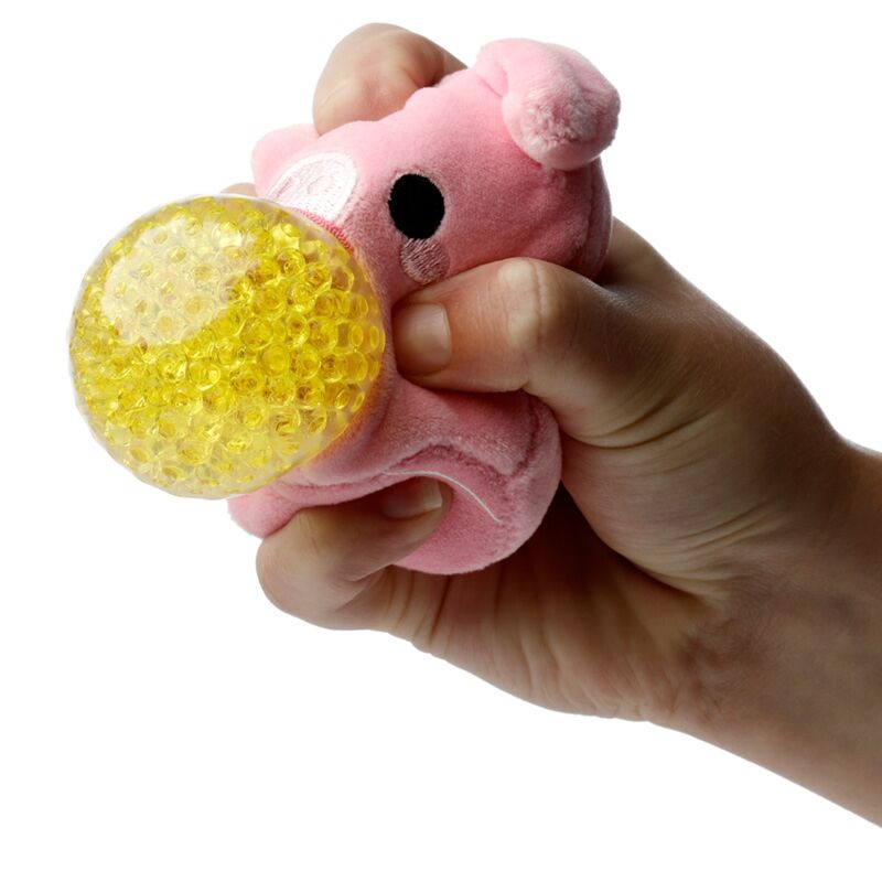 Uma mão a apertar um brinquedo Queasy Squeezies Adoramals em forma de porco, mostrando a bola espremível amarela no interior.