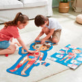 Crianças a montar o puzzle gigante do corpo humano da Hape no chão de uma sala