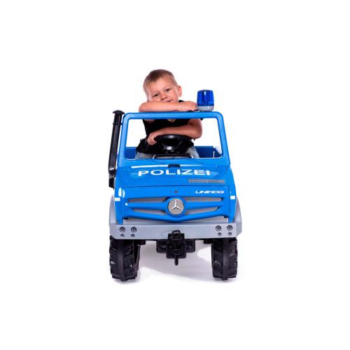 Primeiro plano do rosto de uma criança sorridente ao volante do camião RollyToys Unimog polícia azul, destacando a luz de emergência.