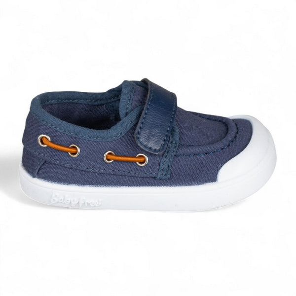 Sapatilha azul marinho estilo náutico para bebé, tipo slip-on com tira de velcro e biqueira branca, vista de perfil.
