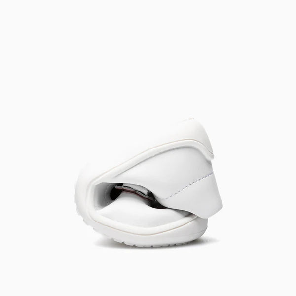 Sapatilha infantil branca dobrada ao meio, evidenciando a extrema flexibilidade e leveza do material.