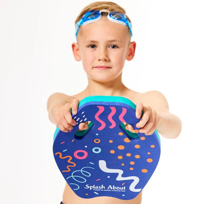 Menino com óculos de natação na testa, a segurar a prancha de natação Splash About - Kickboard Junior de frente para a câmara, mostrando os furos de pega.