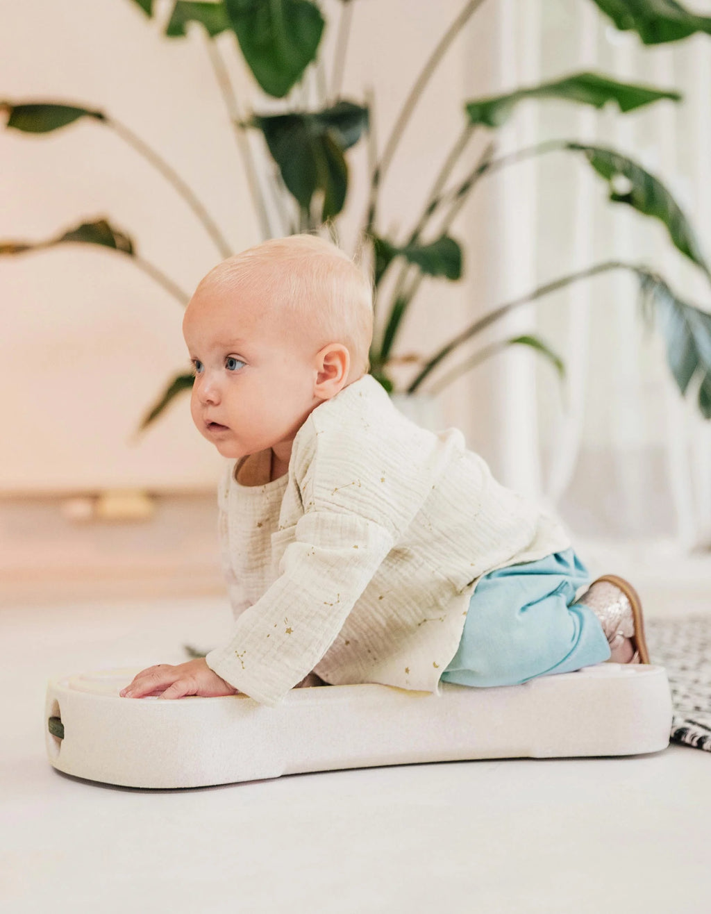 Bebé deitado de barriga sobre a prancha de rolar (Rollbrett) do My First Ride, pronto para impulsionar-se.