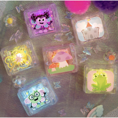 Vista aérea dos seis cubos GloPals acesos, dispostos sobre um tecido macio com decorações de borboletas e flores, exibindo as ilustrações temáticas ligadas.