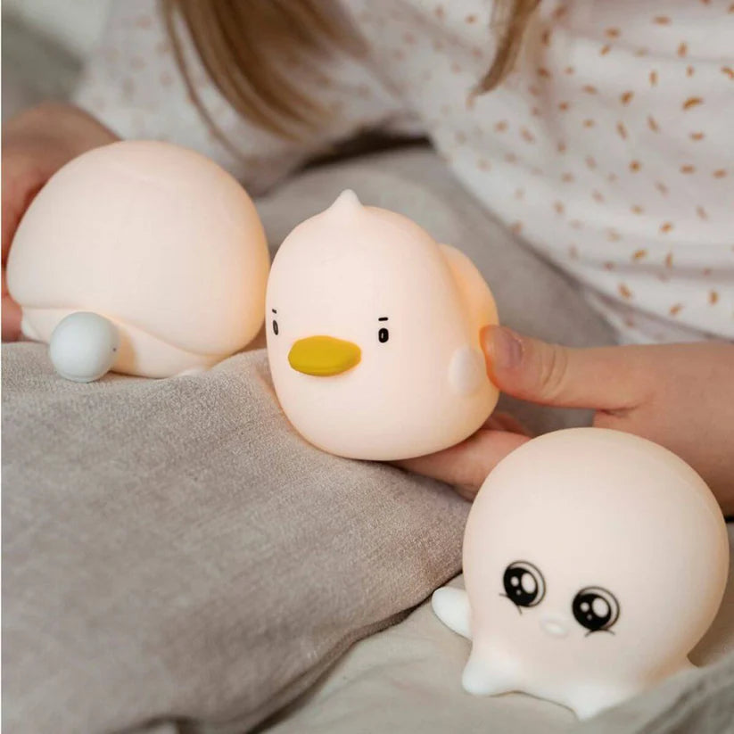Mãos de criança segurando a lâmpada Patinho Rabbit e Friends, com as lâmpadas Tartaruga e Polvo por perto, todas no modo sem luz.