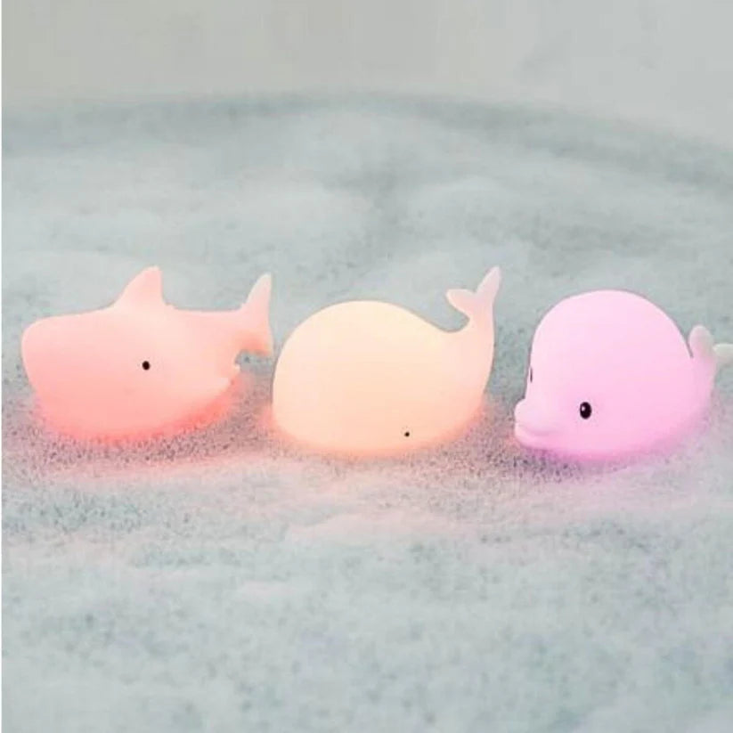 Três lâmpadas Rabbit e Friends Oceano (tubarão, baleia, golfinho) a brilhar com cores suaves num banho de espuma.