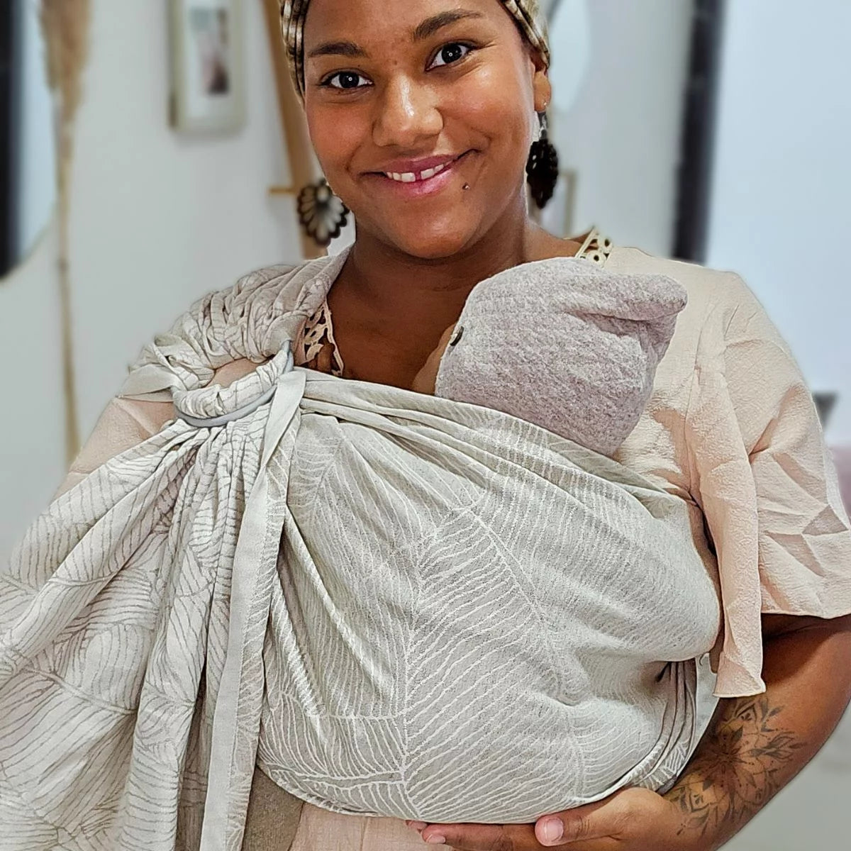 Mulher a carregar bebé de forma ergonómica com o Sling de Argolas Hoppediz Grenada Natural Linen.